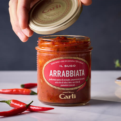 Vaso di Sugo Arrabbiata Fratelli Carli e mano che svita il tappo svelando il contenuto