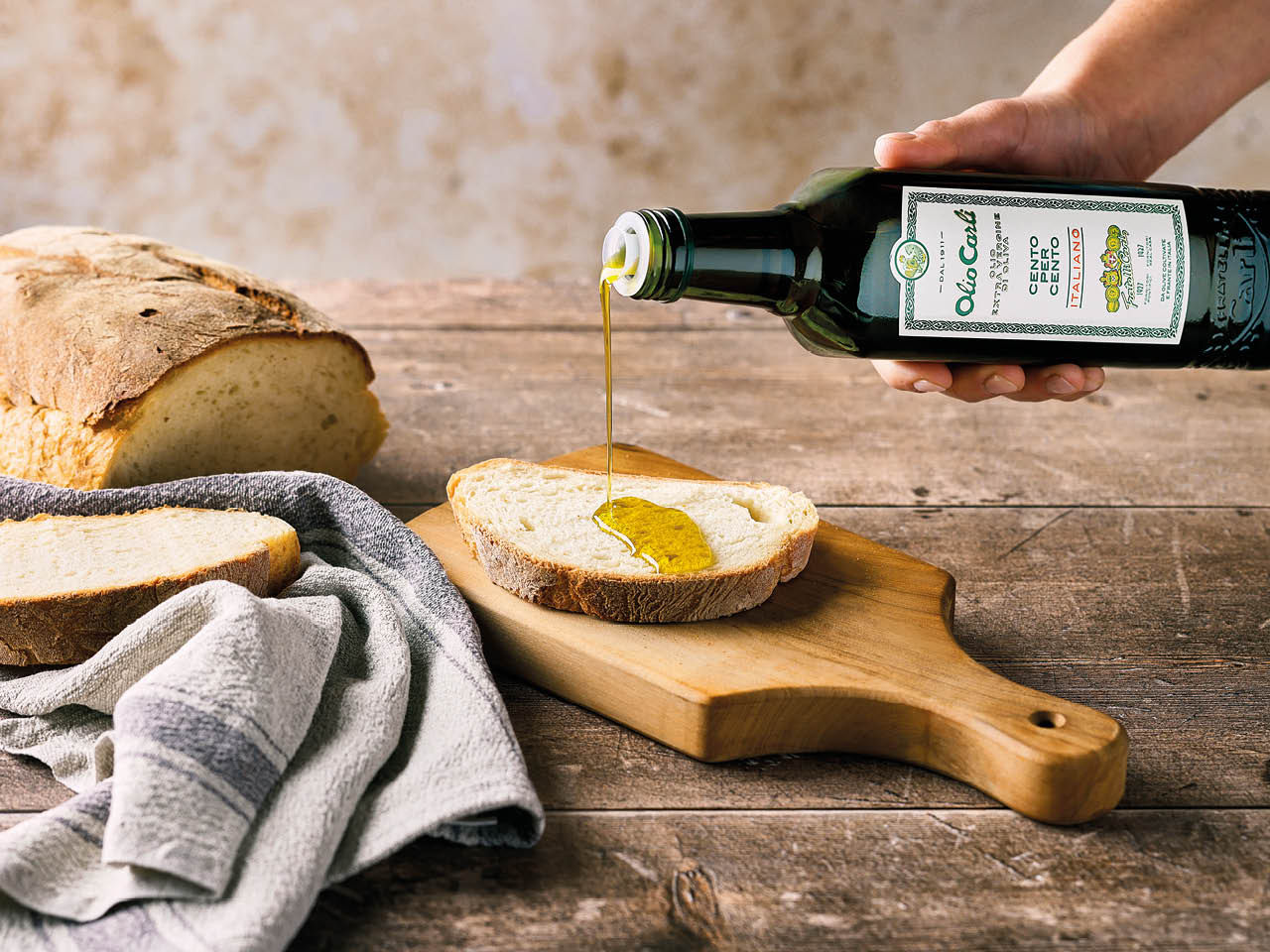 Olio Extra Vergine di Oliva Carli Cento per Cento Italiano versato su una fetta di pane