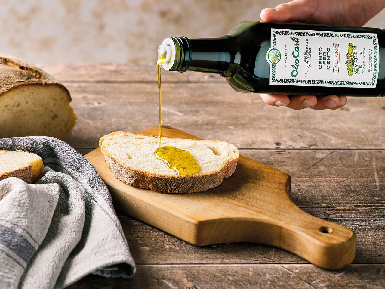 Olio Carli Extra Vergine di Oliva cento per cento italiano versato su una fetta di pane